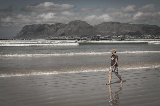 Une femme qui marche sur la plage contre le ciel