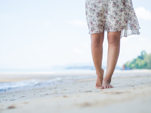 Femme qui marche sur la plage de sable Détail agrandi des pieds féminins