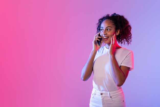 Une femme qui parle au téléphone avec un fond au néon.