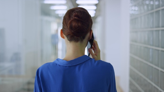 Une femme qui parle au téléphone portable avec une chemise bleue.