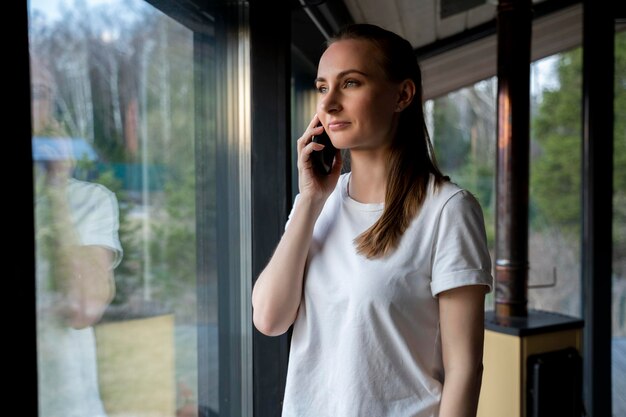 Une femme qui parle au téléphone portable et regarde par la fenêtre.