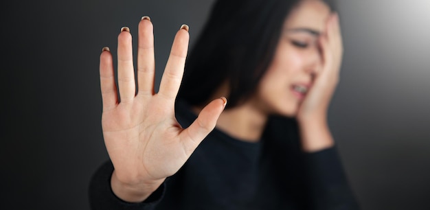 Femme qui pleure montrant un panneau d'arrêt avec sa main