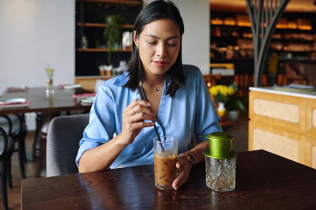 Une femme qui prend du café glacé dans un restaurant.