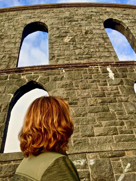 Photo une femme qui regarde contre un vieux mur.