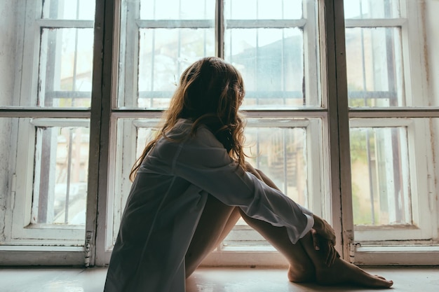 Une femme qui regarde par la fenêtre.