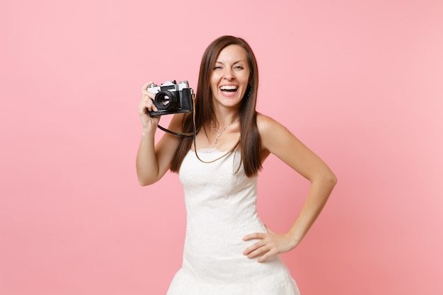 Femme qui rit en robe blanche tenant un appareil photo vintage rétro, choisissant le personnel, photographe