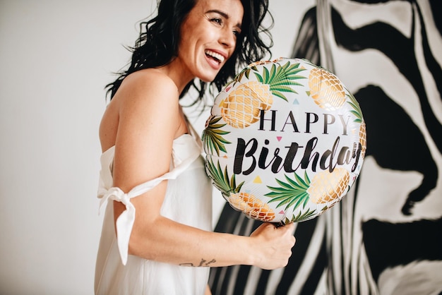 Photo une femme qui rit tenant une décoration d'anniversaire à la maison
