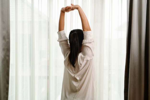 Femme qui s&#39;étend dans la chambre après le réveil, vue arrière