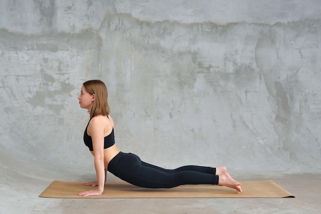 femme qui s'étend dans la pose de Cobra, faire de l'exercice Bhujangasana, pratiquer le yoga.