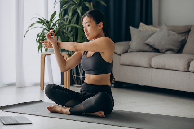 Femme qui s'étend sur un tapis de yoga à la maison