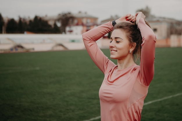 Femme qui s'étire et fait des exercices au stade