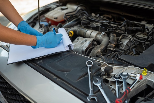 Femme qui travaille comme mécanicienne dans un service automobile réparant le châssis d'une voiture à l'aide d'une clé