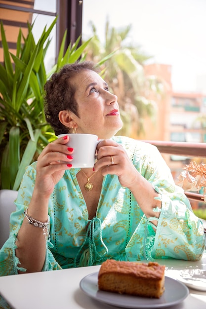 Femme qui a vaincu le cancer prenant un café sur sa terrasse.