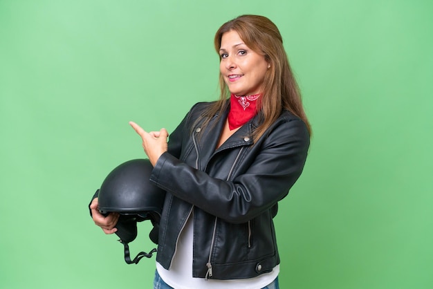 Femme de race blanche d'âge moyen avec un casque de moto sur fond isolé pointant vers l'arrière