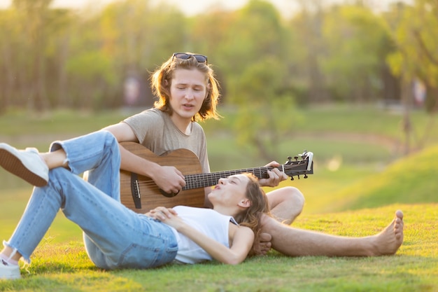 Une femme de race blanche et un bel homme passent du temps ensemble en camping nature et jouent de la guitare.