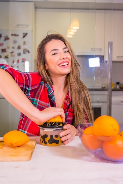 Femme de race blanche blonde ayant un jus d'orange frais pour le petit déjeuner dans sa cuisine