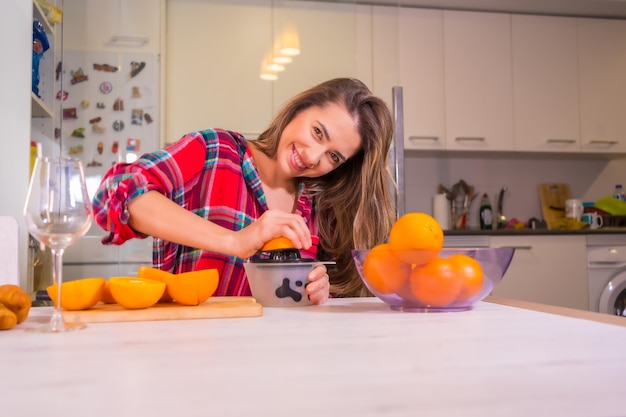 Femme de race blanche blonde ayant un jus d'orange frais pour le petit déjeuner dans sa cuisine