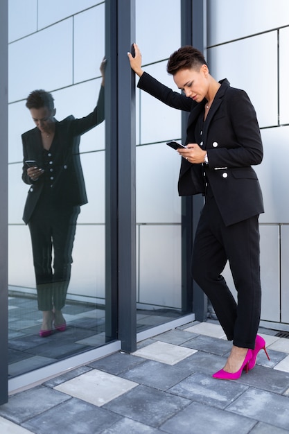 Femme de race blanche dans des vêtements de bureau attend un collègue près de l'immeuble de bureaux