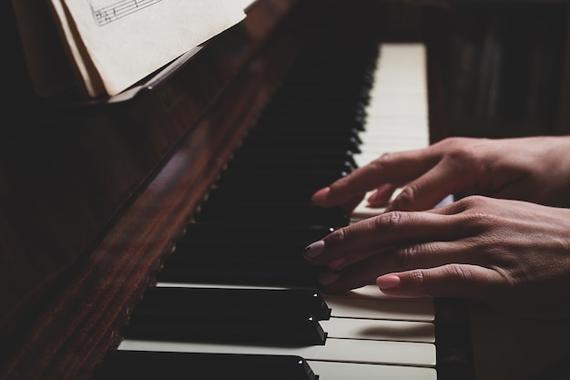 Femme de race blanche jouant du piano en gros plan sombre
