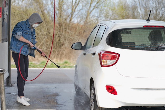 Femme de race blanche lave son véhicule sur un lave-auto en libre-service