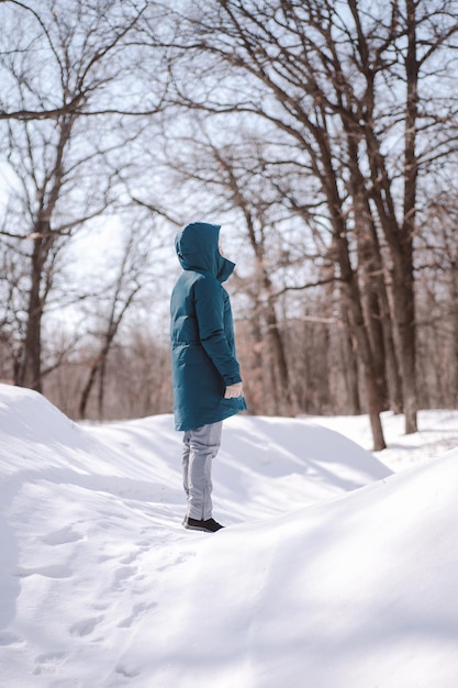 Une femme de race blanche marche à travers une forêt enneigée, une jeune femme se tient sur une route au milieu de la forêt et...