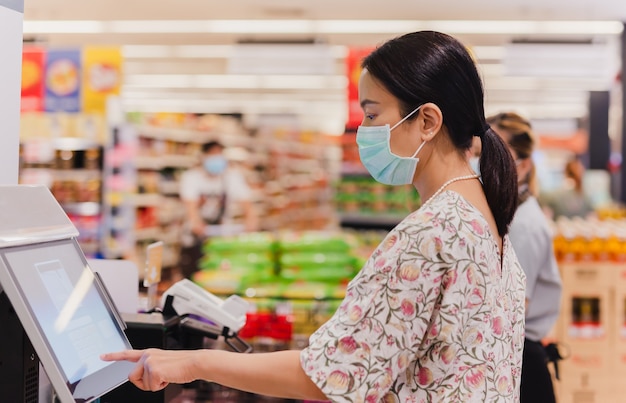 Une femme de race blanche utilise un comptoir de caisse libre-service au supermarché d'épicerie