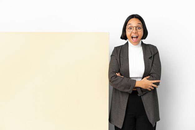 Femme de race mixte jeune entreprise avec une grande bannière sur fond isolé avec une expression faciale surprise