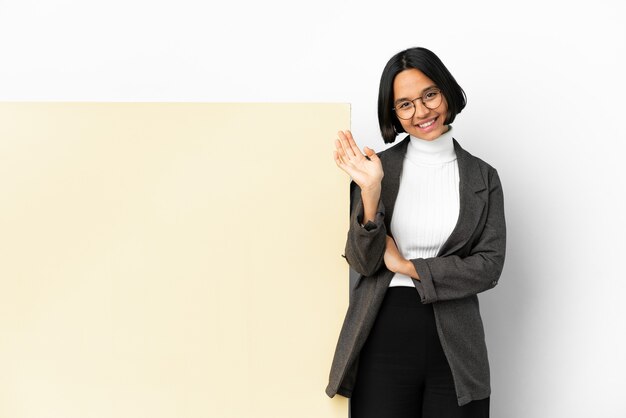 Femme de race mixte jeune entreprise avec une grande bannière sur fond isolé saluant avec la main avec une expression heureuse