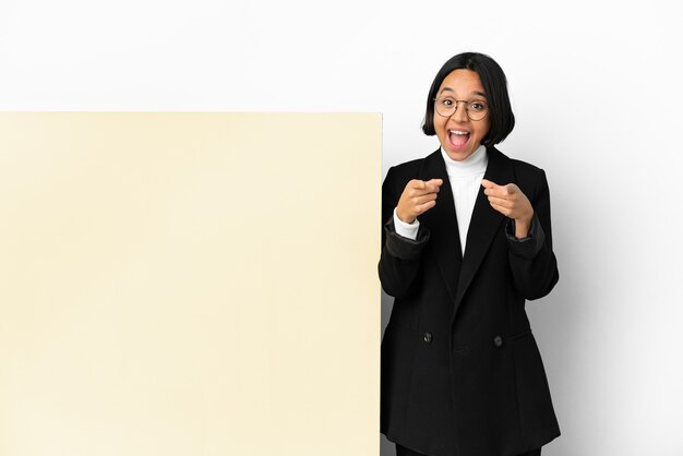 Femme de race mixte jeune entreprise avec une grande bannière sur fond isolé surpris et pointant vers l'avant