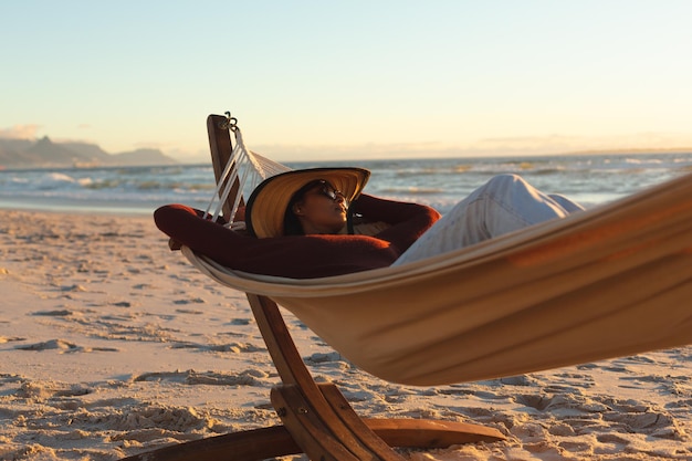Femme de race mixte en vacances à la plage allongée dans un hamac. loisirs en plein air sains au bord de la mer.