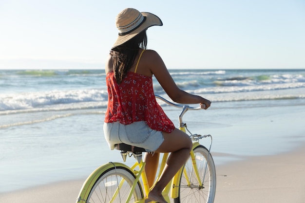 Femme de race mixte en vacances à la plage à vélo sur le sable au bord de la mer. vacances de loisirs en plein air au bord de la mer.