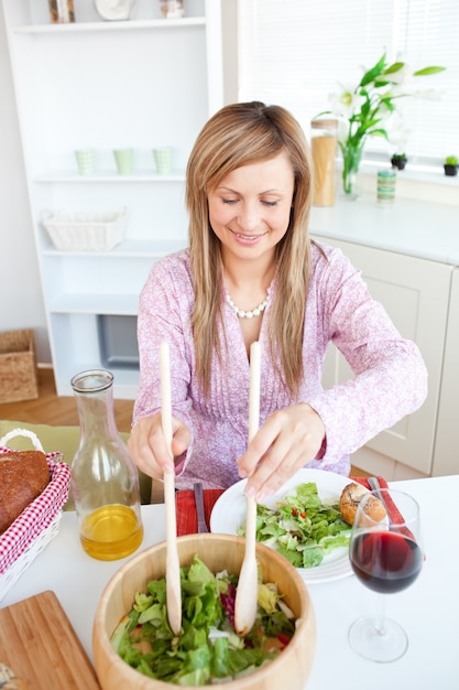 Femme radiante, manger de la salade dans la cuisine