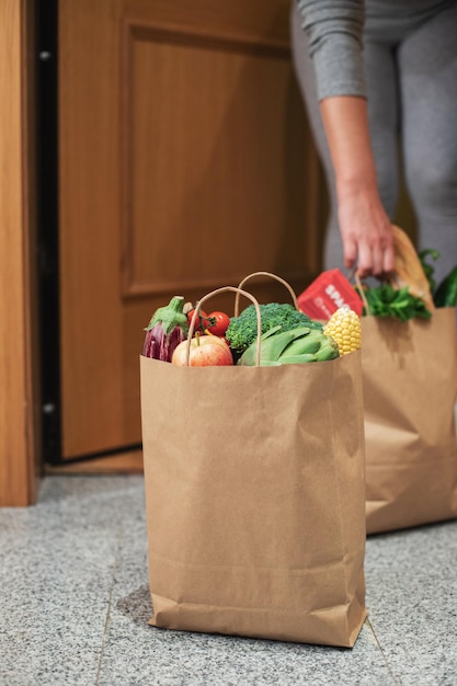 Une femme ramasse un sac de nourriture à la porte de sa maison. Coronavirus. Quarantaine. Restez à la maison, achats en ligne. Livraison de légumes et de fruits pendant la quarantaine et l'auto-isolement