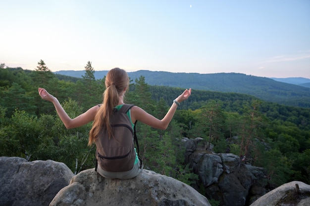 Femme randonneur méditant seul sur une falaise de montagne rocheuse profitant de la vue sur la nature du soir sur le sentier sauvage Mode de vie actif concept