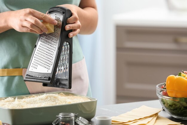 Femme râper du fromage pour les lasagnes en cuisine