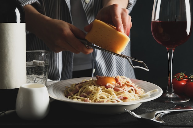 Femme râper le fromage sur les pâtes. Composition de pâtes alimentaires