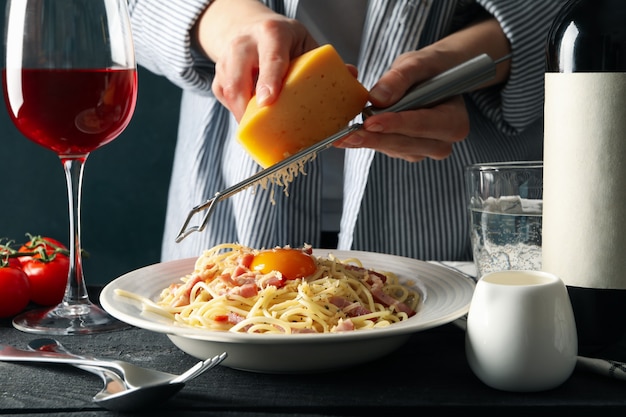 Femme râper le fromage sur les pâtes. Composition de pâtes alimentaires