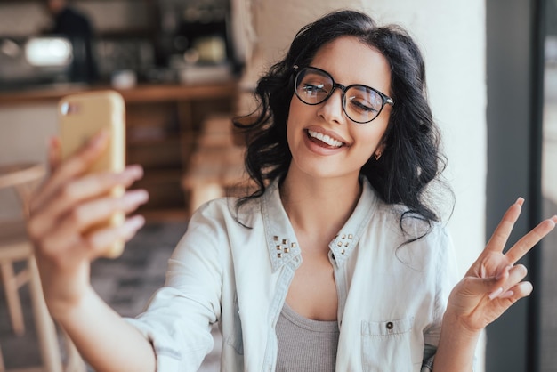 Femme ravie prenant selfie au café