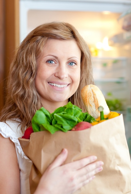 Femme rayonnante tenant un sac d&#39;épicerie