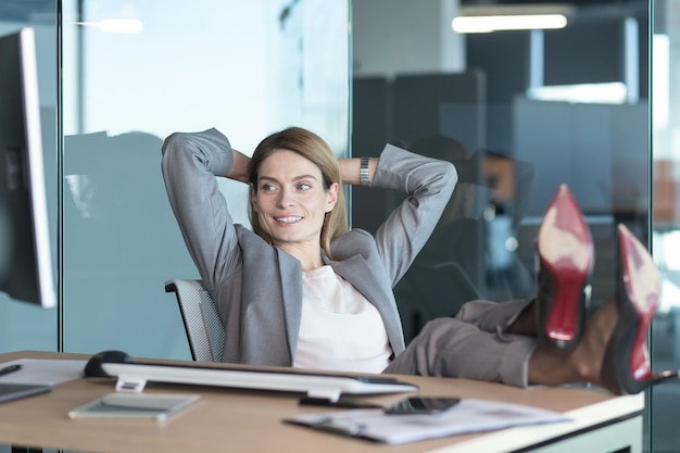 Femme réalisatrice se reposant et rêvant au travail femme d'affaires jetant ses mains derrière la tête et les pieds sur la table se reposant le jour au travail