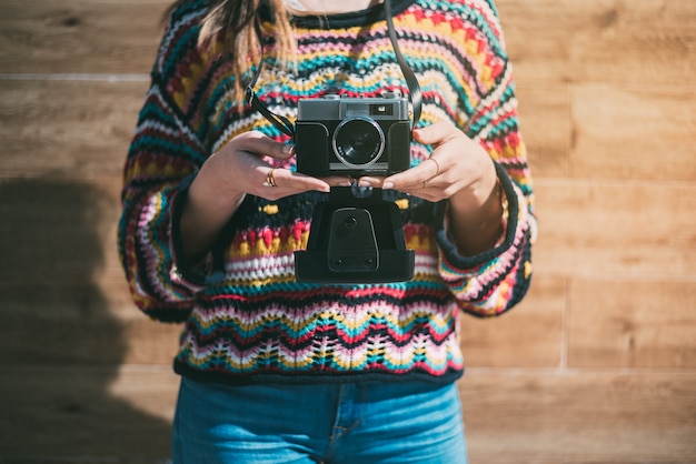 Femme recadrée avec vieil appareil photo vintage et pull coloré