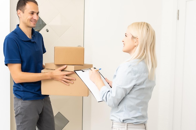 femme recevant des boîtes du facteur à la porte dans le concept de livraison à domicile. La femme a reçu le colis du facteur à la maison. Facteur donnant une boîte en carton à une jeune femme.