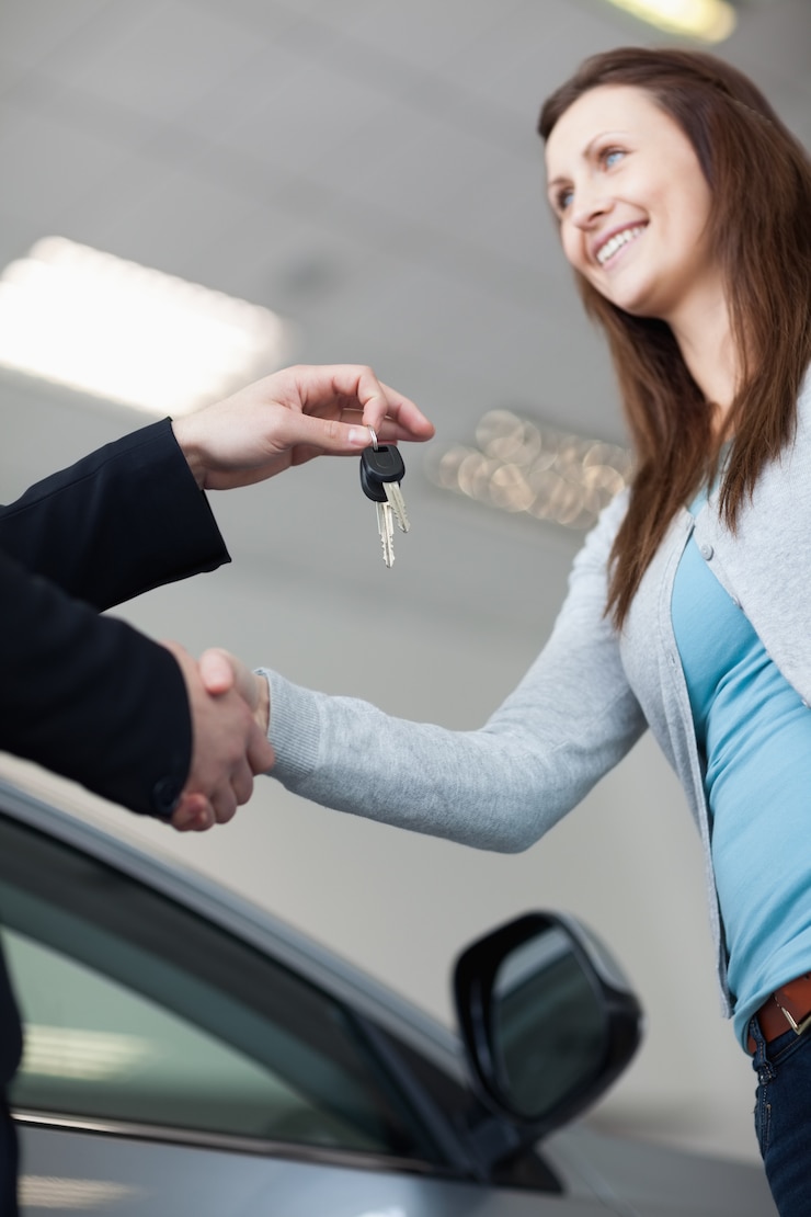 Photo femme recevant les clés de la voiture en serrant la main dans un garage