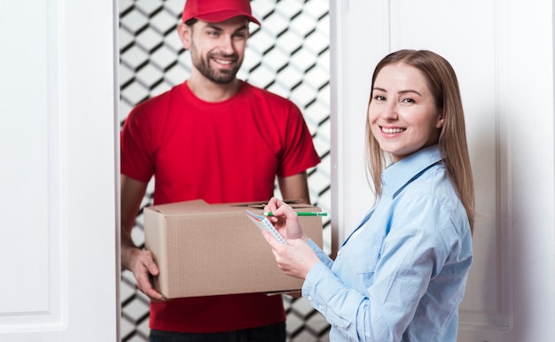 Photo femme recevant un colis du courrier et signant les formulaires