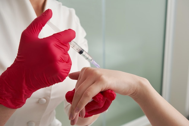 femme recevant des injections de remplissage rajeunissantes dans sa main. Esthéticienne injectant un produit de remplissage dans la peau de la main