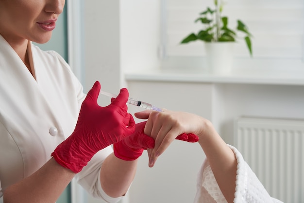 femme recevant des injections de remplissage rajeunissantes dans sa main. Esthéticienne injectant un produit de remplissage dans la peau de la main