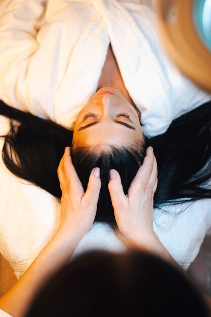 Femme recevant le massage du cuir chevelu dans le salon spa