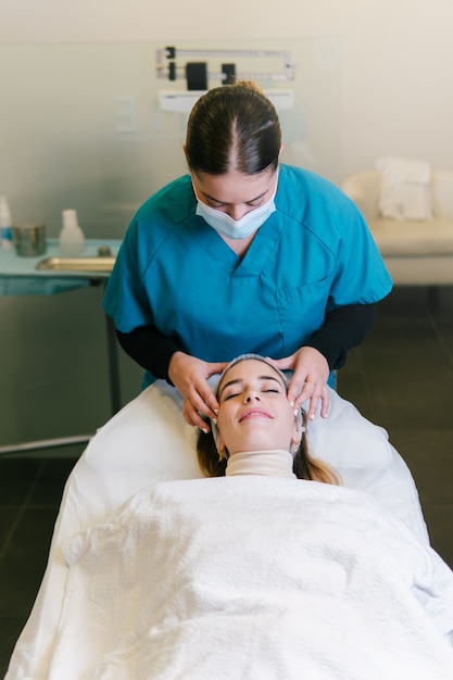 Femme recevant un massage du visage et un traitement dans une clinique de beauté privée