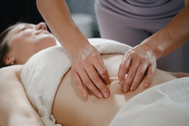 Une femme recevant un massage professionnel du ventre en gros plan dans un centre de bien-être