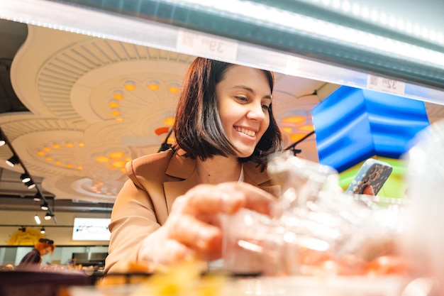 Femme à la recherche de produits sur une étagère Couple de clients faisant leurs courses avec une liste de contrôle